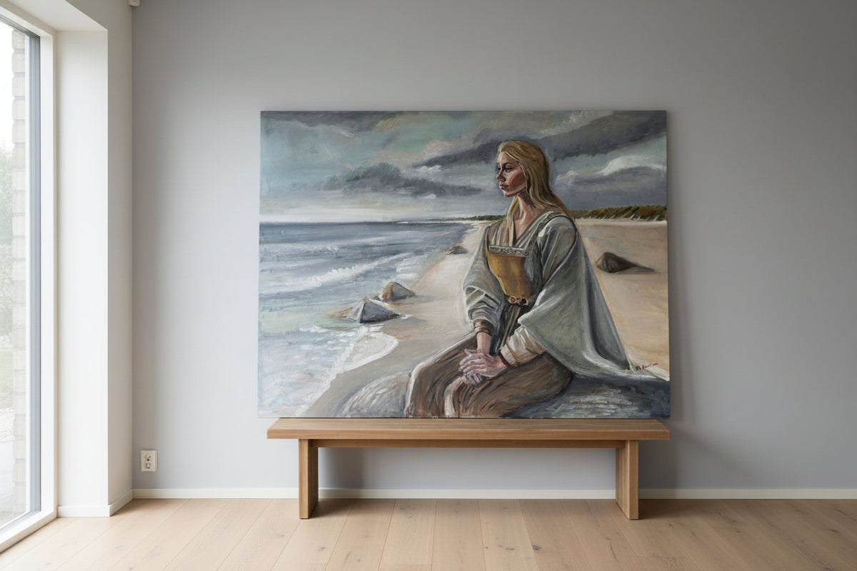Painting of a woman sitting on a beach with mountains in the background, displayed in a room.